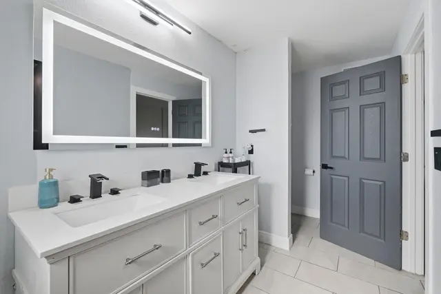 Modern double vanity bathroom with illuminated mirror and sleek finishes at The Clue House
