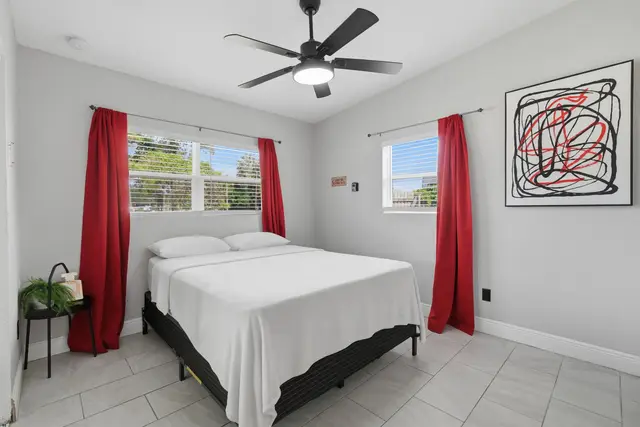 Bright modern bedroom with bold accents, natural light, and cooling ceiling fan at The Clue House