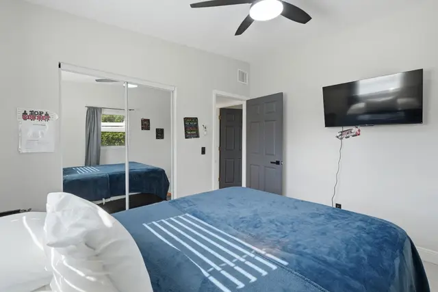 Bright, cozy bedroom with TV, mirrored closet, and airy high ceilings at The Clue House
