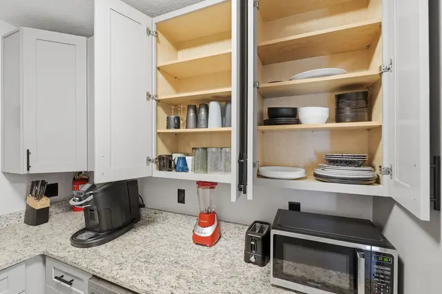 Stocked kitchen with coffee maker, microwave, and organized dishware at The Clue House