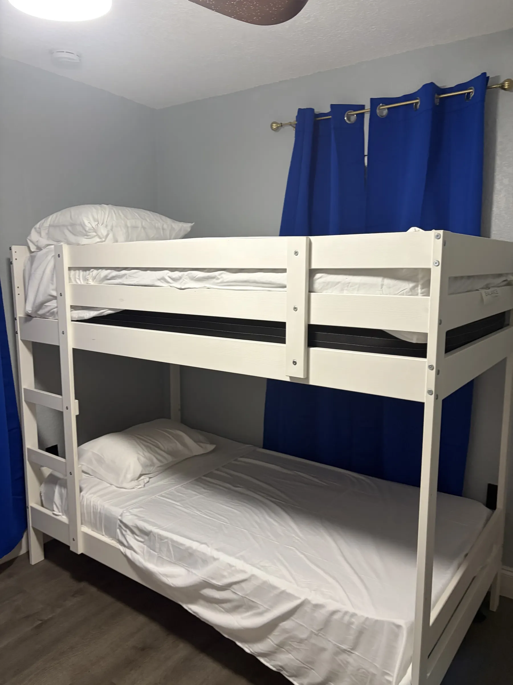 Bright bunk room with twin beds, blackout curtains, and ceiling fan at Downtown & Stadium Cozy Retreat