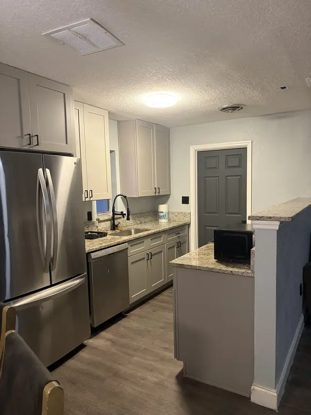 Modern kitchen with stainless appliances, granite tops, and breakfast bar. at Downtown & Stadium Cozy Retreat