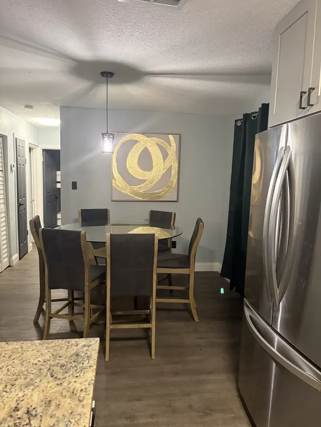 Sleek dining nook with stainless fridge, modern art & wood floors at Downtown & Stadium Cozy Retreat