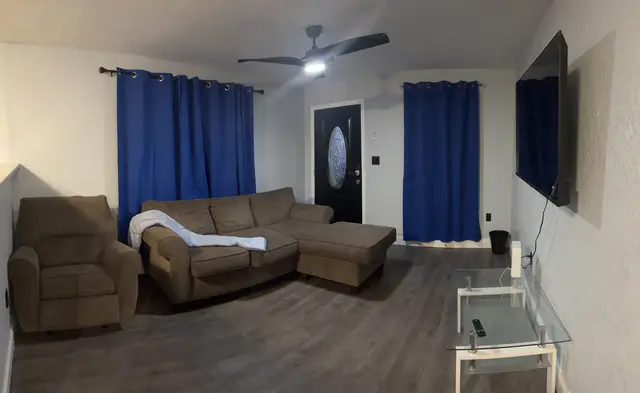 Cozy lounge with sectional, wall‑mounted TV, blackout drapes & fan at Downtown & Stadium Cozy Retreat