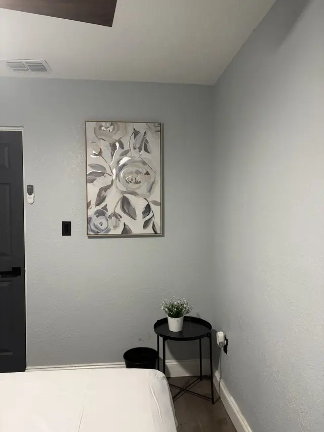 Serene, minimalist bedroom with modern art and cozy bedside table. at Downtown & Stadium Cozy Retreat