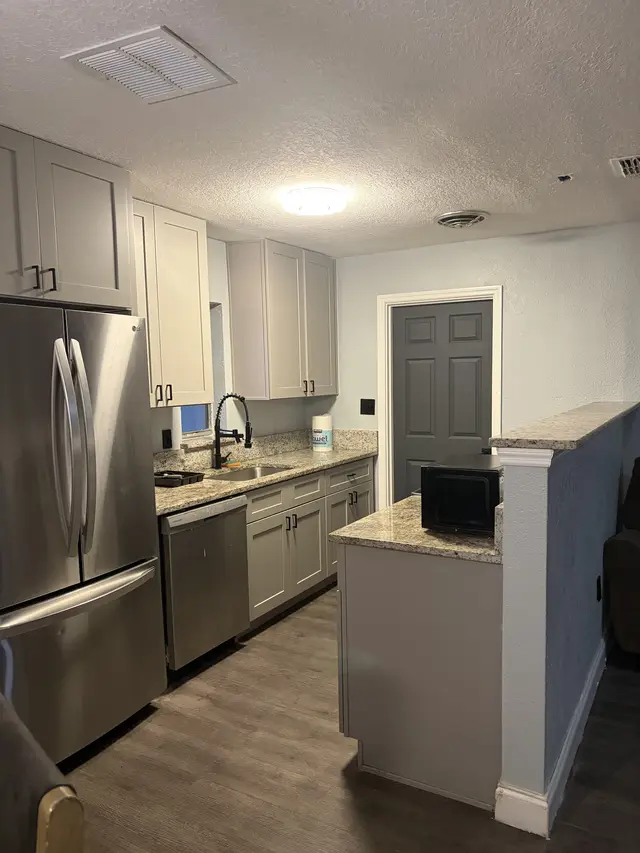 Modern galley kitchen with granite, stainless & ample storage at Downtown & Stadium Cozy Retreat