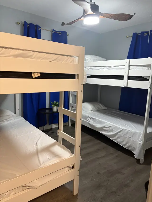 Bright bunk room sleeps 4 with sturdy bunks, fan, and blue drapes. at Downtown & Stadium Cozy Retreat