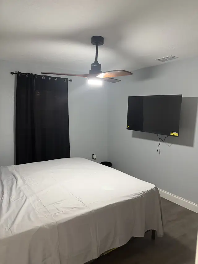 Cozy gray bedroom with king bed, blackout drapes, fan and smart TV at Downtown & Stadium Cozy Retreat