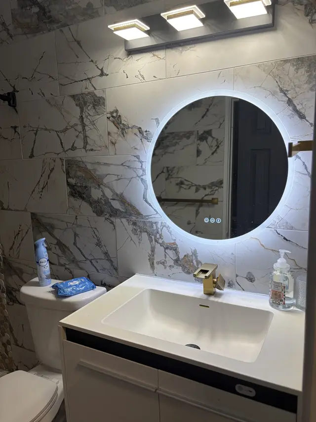 Sleek bath with LED mirror, marble tile, and brass accents at Downtown & Stadium Cozy Retreat