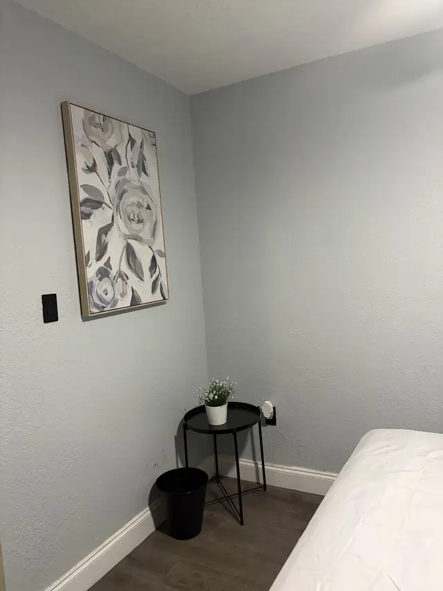 Calm, minimalist bedroom with floral art and modern side table at Downtown & Stadium Cozy Retreat