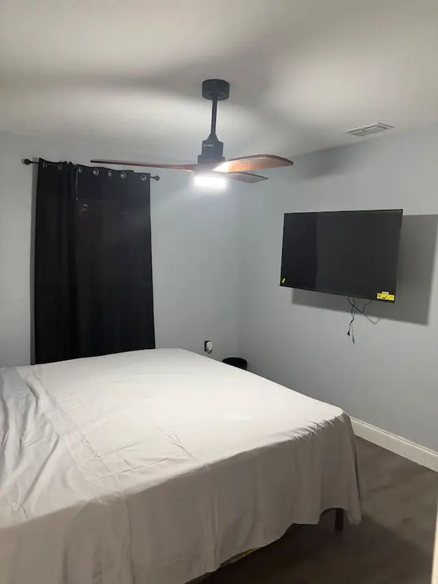 Cozy gray bedroom with king bed, blackout drapes, fan and smart TV at Downtown & Stadium Cozy Retreat