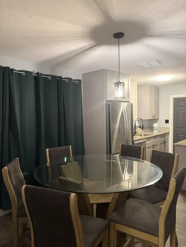 Modern kitchen-diner with glass table, stainless appliances, and chic lighting at Downtown & Stadium Cozy Retreat